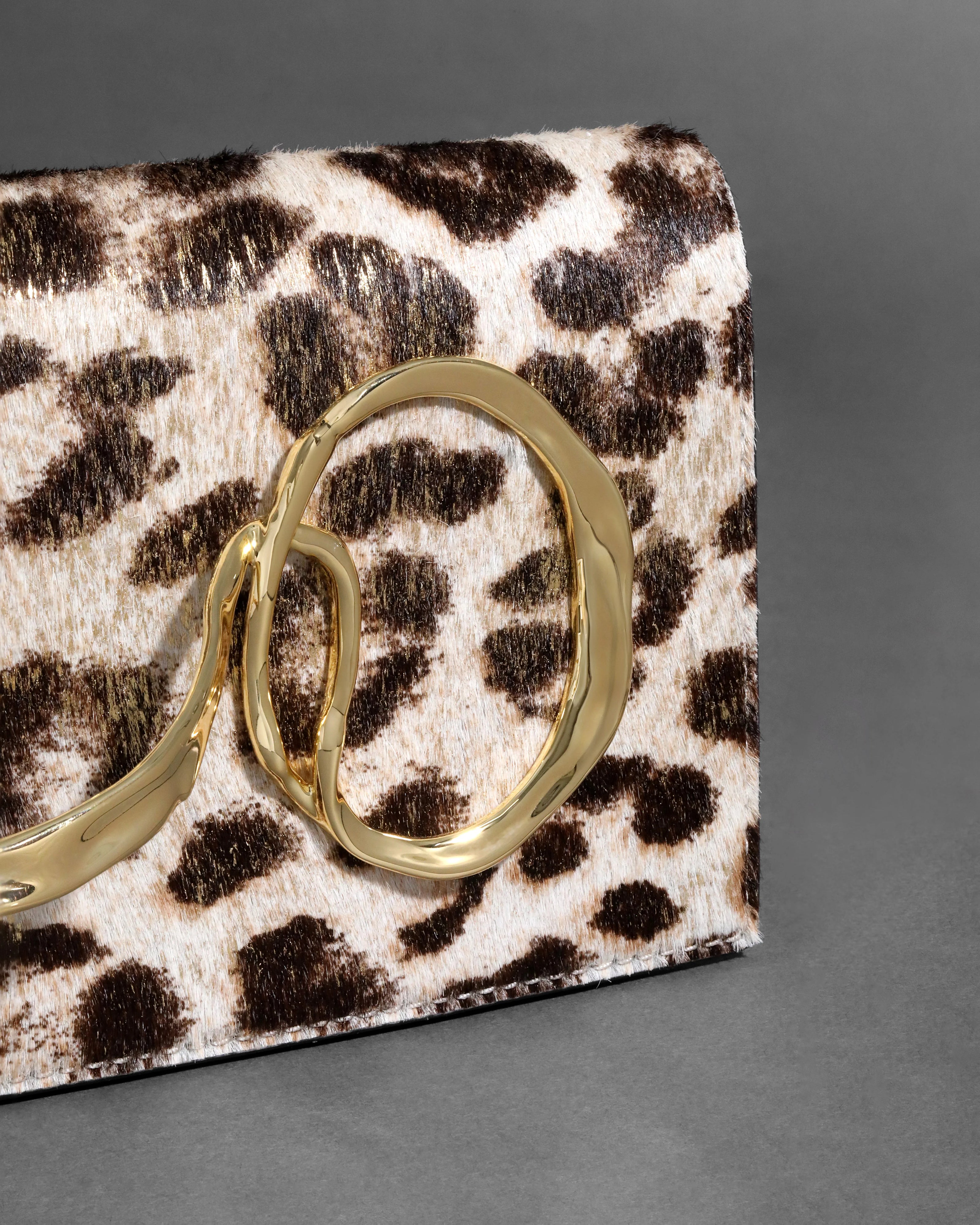 TWISTED GOLD SIDE HANDLE CLUTCH PURSE IN METALLIC LEOPARD